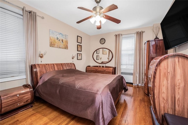 bedroom with hardwood / wood-style floors, radiator heating unit, and ceiling fan