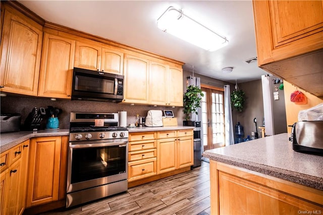 kitchen with tasteful backsplash, french doors, stainless steel appliances, and light hardwood / wood-style floors