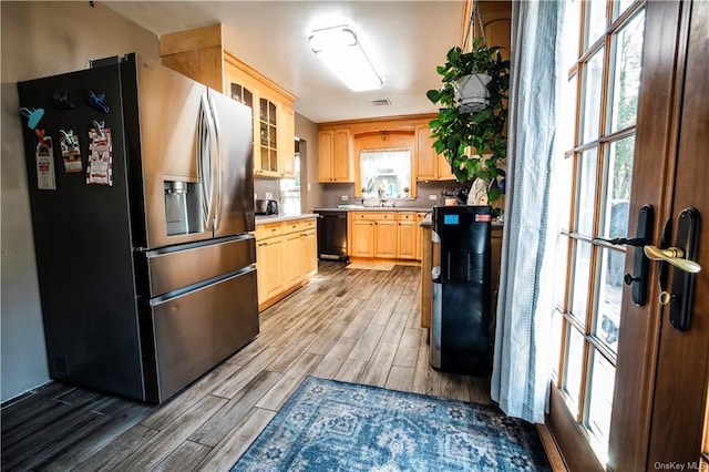 kitchen featuring stainless steel refrigerator with ice dispenser, light brown cabinetry, a healthy amount of sunlight, dishwasher, and light hardwood / wood-style floors