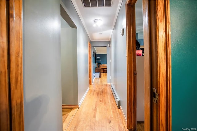 hallway featuring light wood-type flooring, ornamental molding, and a baseboard heating unit