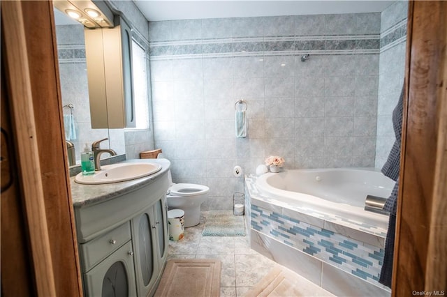 bathroom with a relaxing tiled tub, tile patterned floors, toilet, vanity, and tile walls