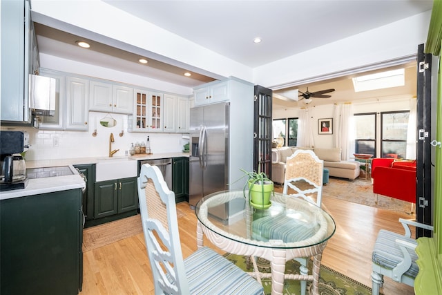 dining room with a skylight, ceiling fan, light hardwood / wood-style flooring, and sink