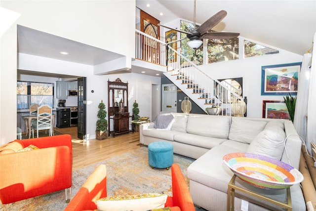 living room featuring hardwood / wood-style flooring, ceiling fan, and high vaulted ceiling