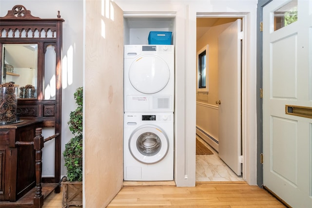 laundry area with stacked washer and dryer, light hardwood / wood-style floors, and a baseboard radiator