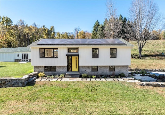 raised ranch with solar panels and a front yard