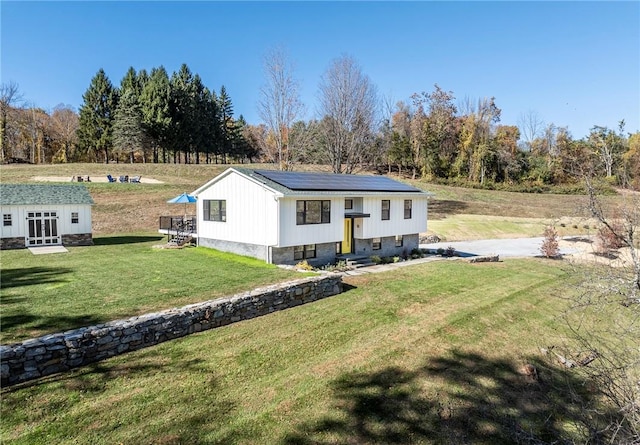 view of front of house featuring an outbuilding, a front yard, and solar panels