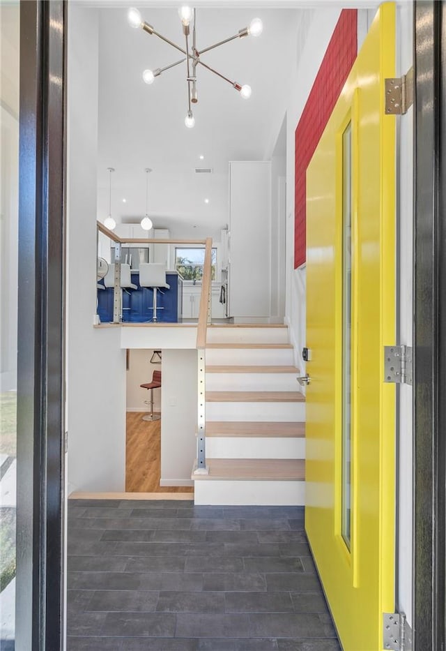 stairway with a notable chandelier, wood-type flooring, and elevator