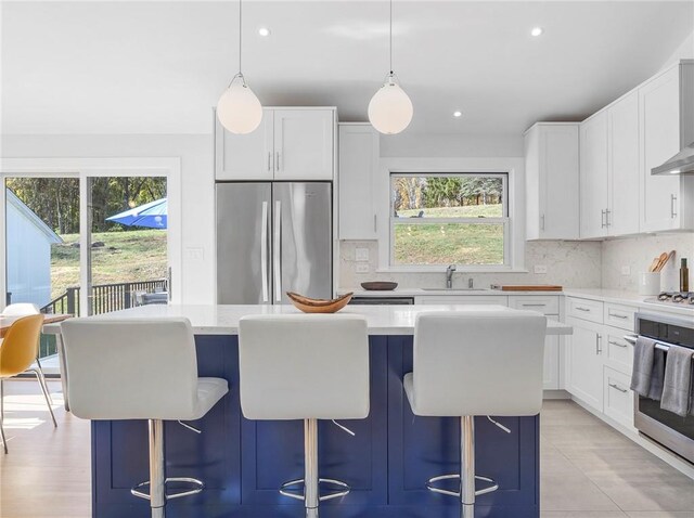 kitchen with hanging light fixtures, white cabinets, stainless steel appliances, and a kitchen island