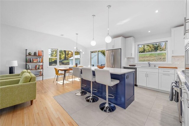 kitchen featuring appliances with stainless steel finishes, white cabinetry, hanging light fixtures, and a kitchen island