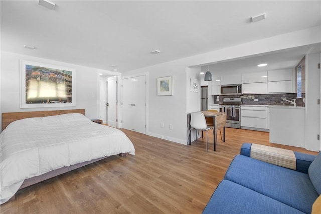 bedroom featuring stainless steel fridge and light wood-type flooring