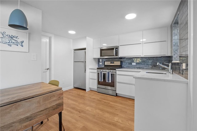 kitchen featuring sink, white cabinets, pendant lighting, and appliances with stainless steel finishes