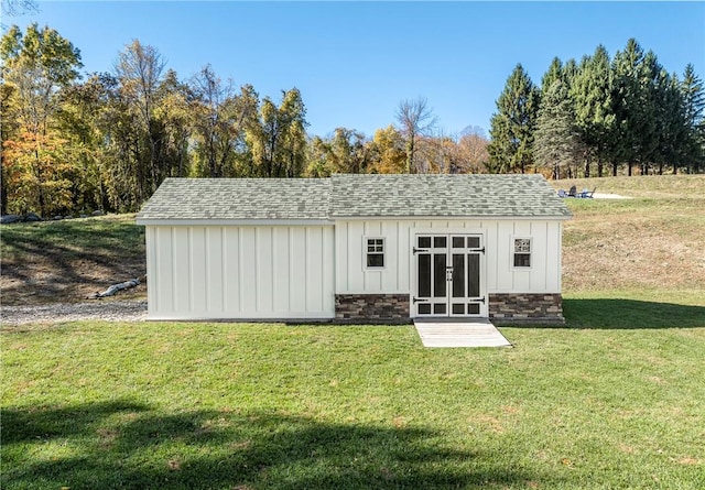 view of outdoor structure with a lawn and french doors