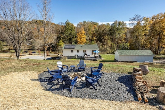 view of yard with a deck, an outdoor structure, and an outdoor fire pit