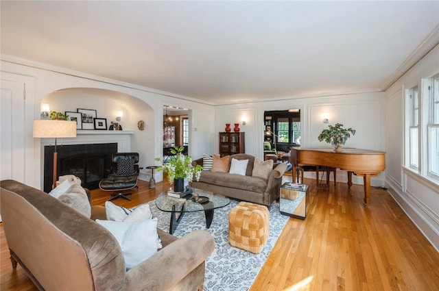 living room featuring a tile fireplace, light hardwood / wood-style flooring, and ornamental molding