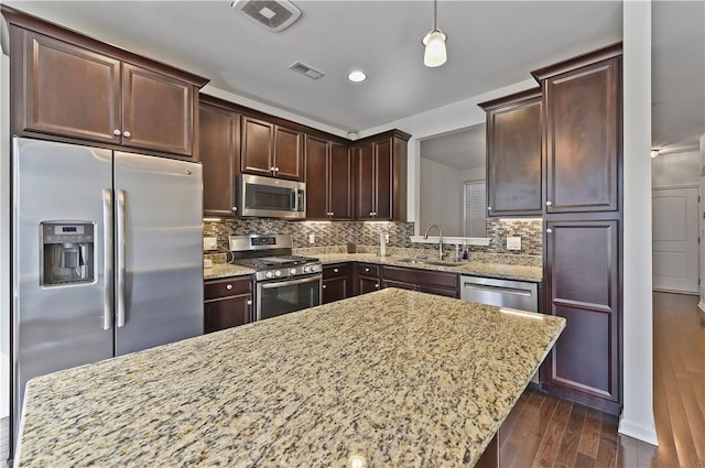 kitchen featuring dark hardwood / wood-style flooring, backsplash, stainless steel appliances, sink, and decorative light fixtures