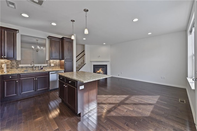 kitchen featuring sink, hanging light fixtures, stainless steel dishwasher, dark hardwood / wood-style floors, and a kitchen island