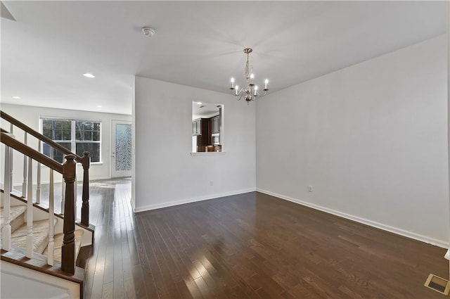 unfurnished living room featuring a chandelier and dark hardwood / wood-style floors