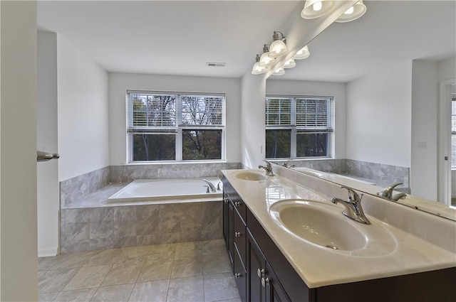 bathroom with tile patterned flooring, vanity, and a relaxing tiled tub