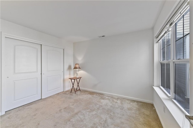 unfurnished bedroom featuring light colored carpet and a closet