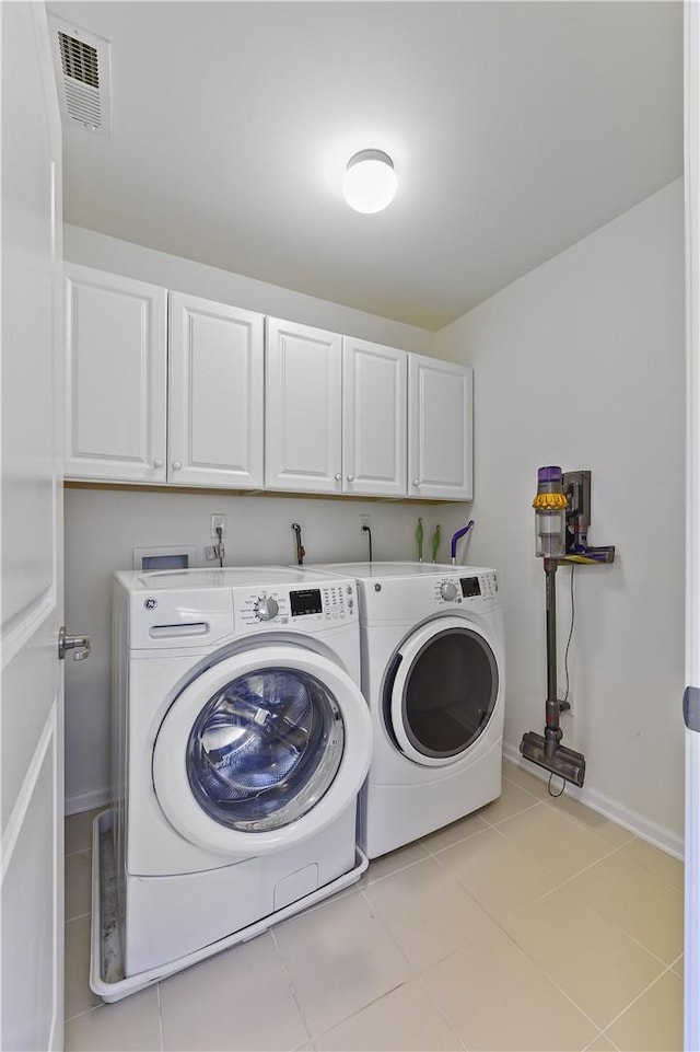 washroom with cabinets, light tile patterned floors, and washing machine and dryer