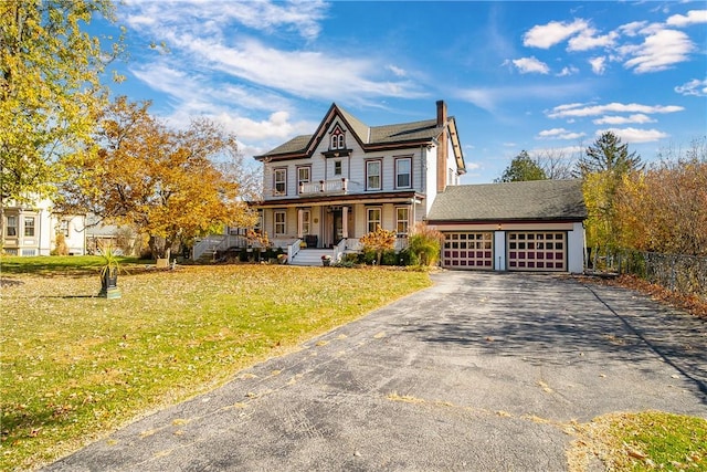 view of front of house with a garage, covered porch, and a front yard