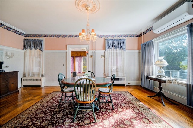 dining room with a wall mounted AC, hardwood / wood-style floors, radiator, and a notable chandelier