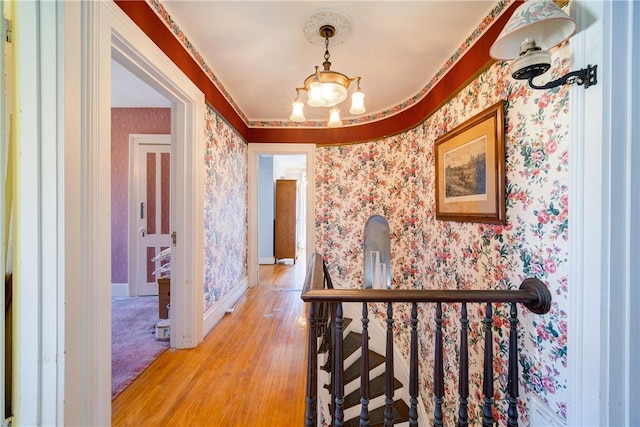 hall with a chandelier, ornamental molding, and light hardwood / wood-style flooring