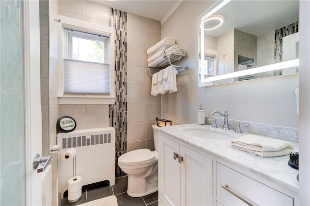 bathroom with tile patterned floors, vanity, tile walls, radiator heating unit, and toilet