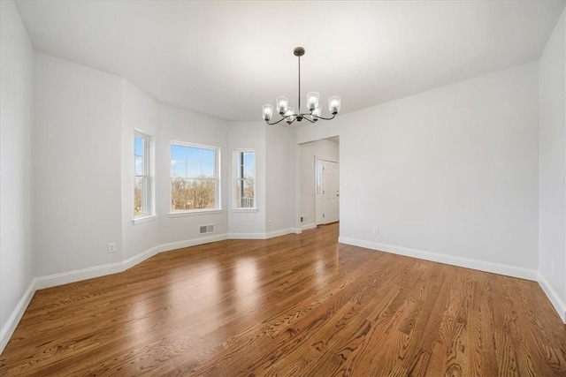 unfurnished room with hardwood / wood-style floors and a notable chandelier