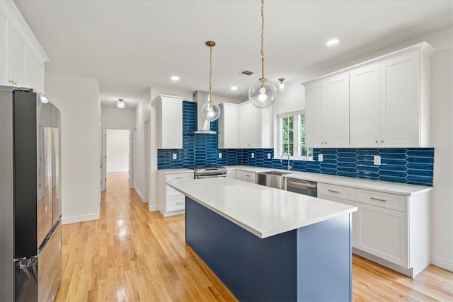 kitchen with white cabinets, a center island, light wood-type flooring, and appliances with stainless steel finishes