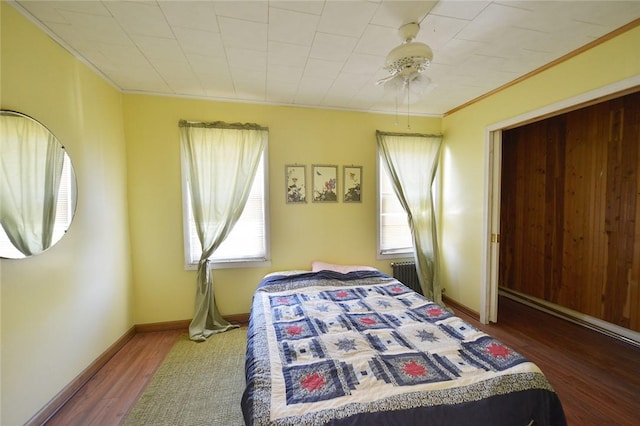 bedroom with ceiling fan, radiator heating unit, wood-type flooring, and ornamental molding