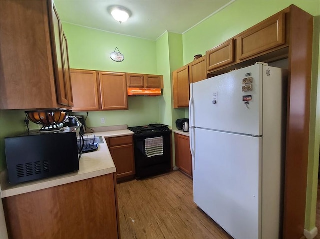 kitchen with light wood-type flooring, white fridge, and black range oven