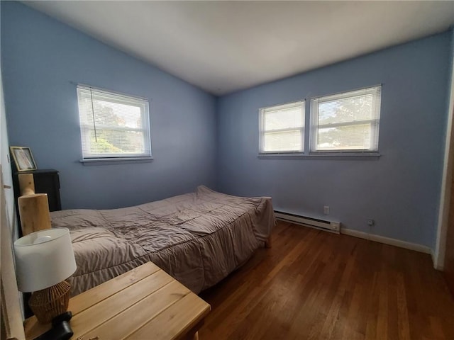 bedroom with dark hardwood / wood-style flooring, baseboard heating, and multiple windows