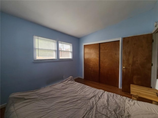 unfurnished bedroom featuring a closet, wood-type flooring, and vaulted ceiling