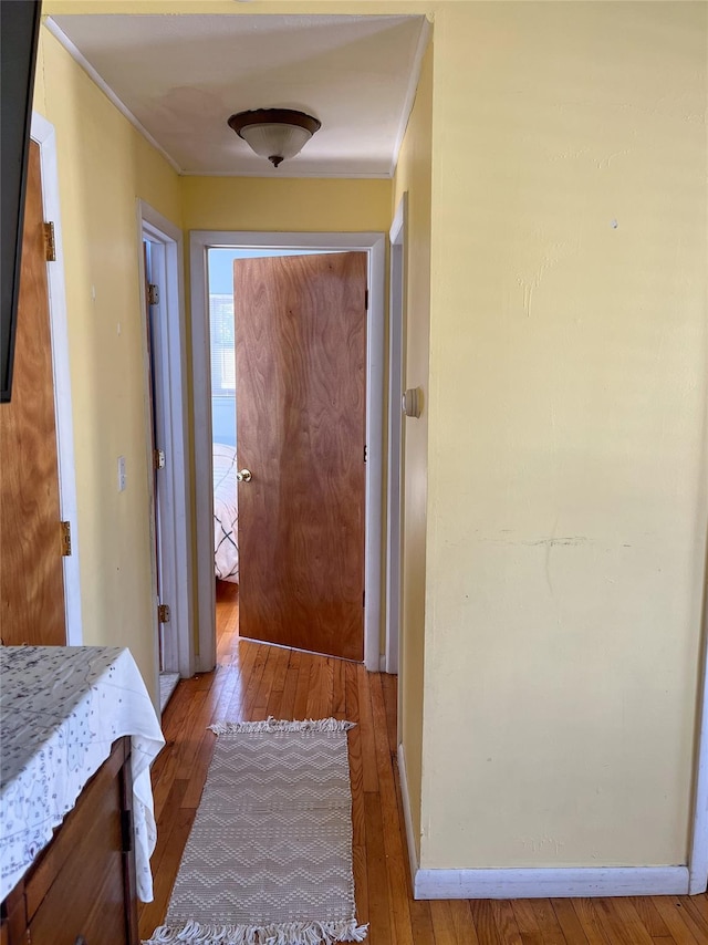 corridor with ornamental molding and light hardwood / wood-style floors