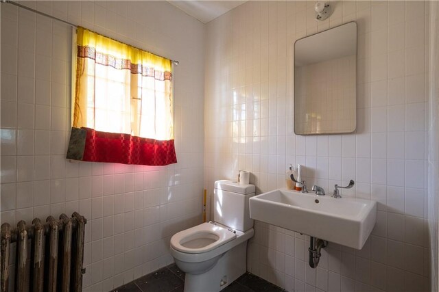 24921 State Highway 97, Hancock, NY 13783 - bathroom with sink, toilet, radiator heating unit, and tile walls