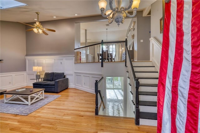 interior space featuring a high ceiling, ceiling fan with notable chandelier, and hardwood / wood-style flooring