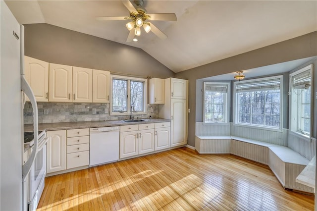 kitchen with white appliances, light hardwood / wood-style flooring, vaulted ceiling, and sink