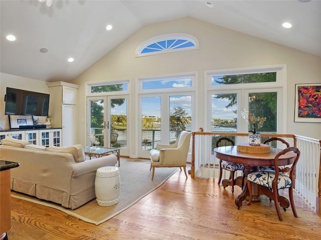 interior space with french doors, light hardwood / wood-style floors, high vaulted ceiling, and a water view