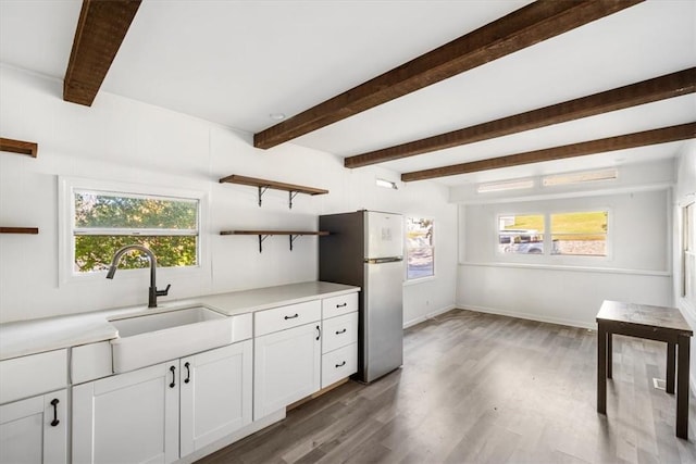 kitchen featuring plenty of natural light, stainless steel fridge, wood-type flooring, and white cabinetry