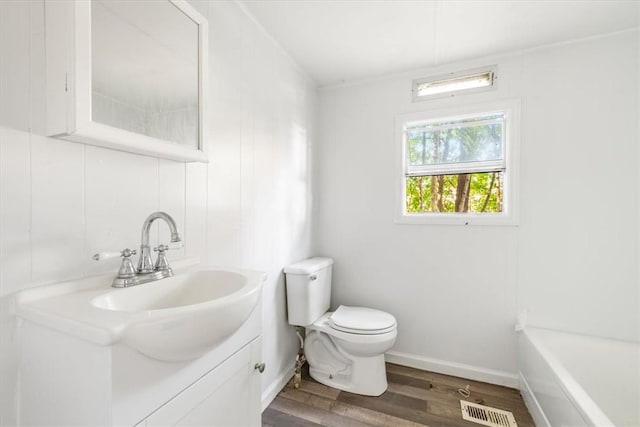 bathroom featuring hardwood / wood-style flooring, vanity, toilet, and a tub