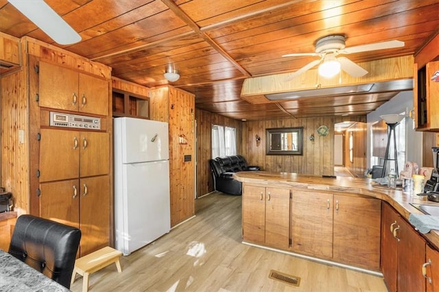 kitchen with wooden walls, plenty of natural light, light hardwood / wood-style floors, and white refrigerator