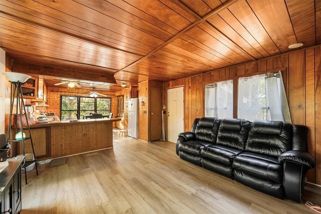 living room with wooden walls, wood ceiling, and light wood-type flooring