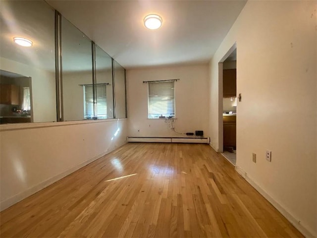 spare room featuring light wood-type flooring and a baseboard heating unit