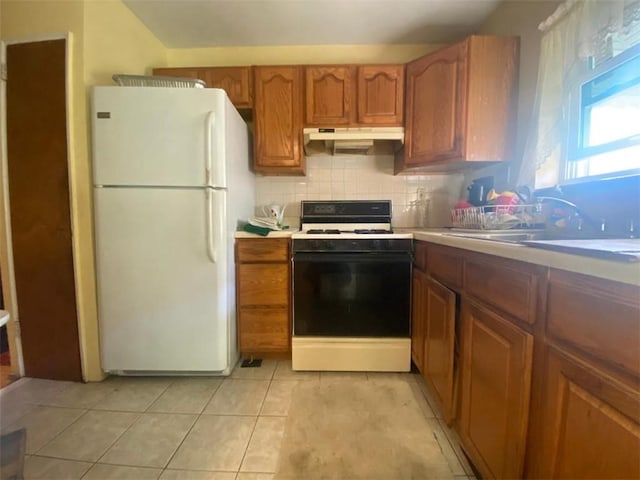 kitchen with light tile patterned floors, white appliances, tasteful backsplash, and sink