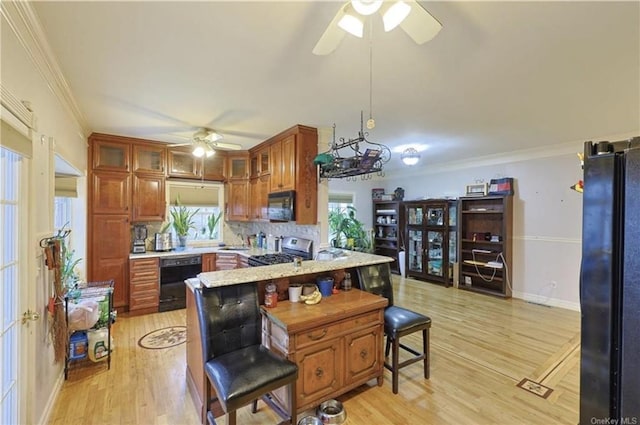 kitchen with black appliances, a kitchen breakfast bar, ornamental molding, light hardwood / wood-style floors, and kitchen peninsula