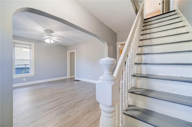 staircase featuring wood-type flooring and ceiling fan