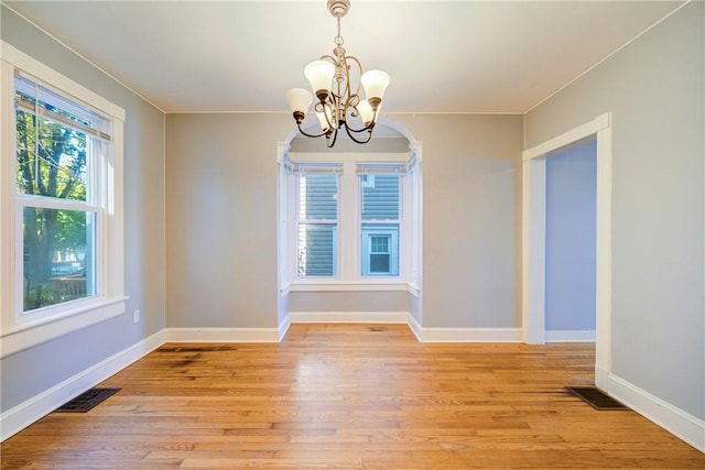 unfurnished dining area featuring a chandelier and light hardwood / wood-style floors