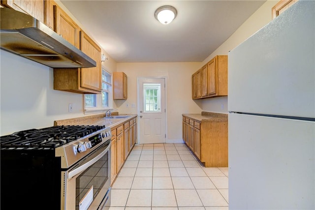 kitchen with stainless steel range with gas cooktop, sink, light tile patterned floors, and white refrigerator