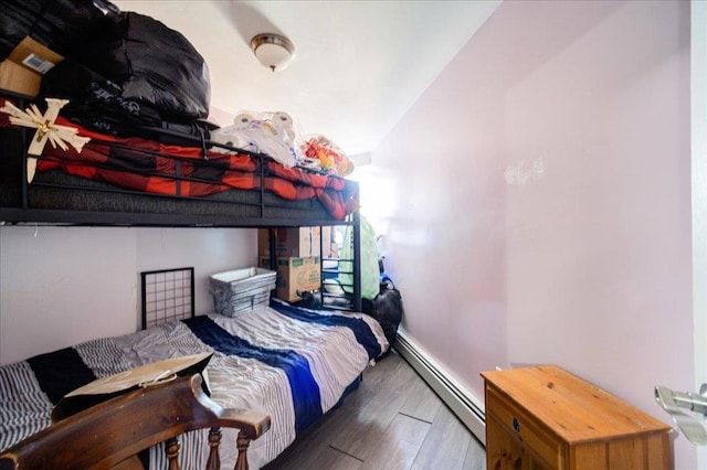 bedroom with baseboard heating and dark wood-type flooring